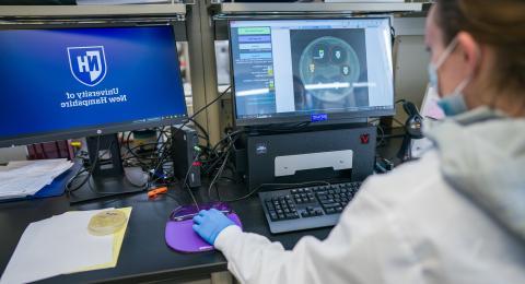 Researcher in a medical mask entering data into a computer