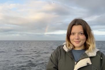 Emma McGuire in front of a rainbow